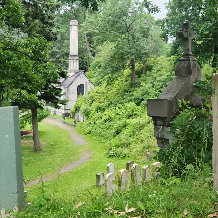 mausoleum in a cemetery with a few gravestones and lush greens